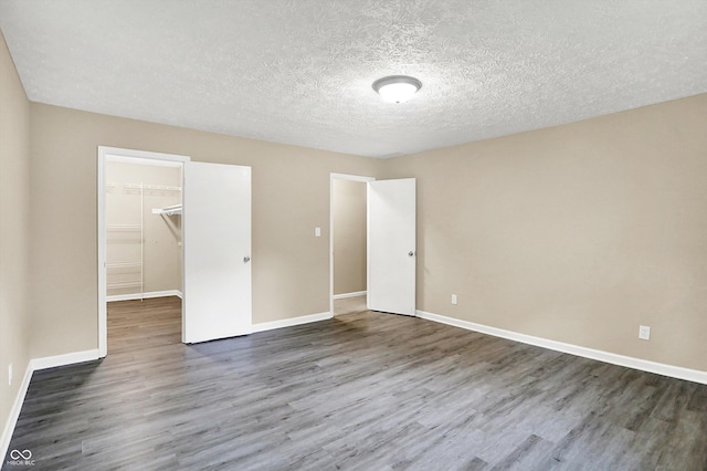 2747 E Midland Rd, Indianapolis, IN 46227 - unfurnished bedroom featuring wood finished floors, a closet, a walk in closet, baseboards, and a textured ceiling