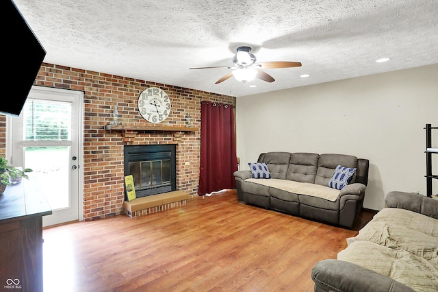 2747 E Midland Rd, Indianapolis, IN 46227 - living room with wood finished floors, a ceiling fan, a textured ceiling, and a brick fireplace