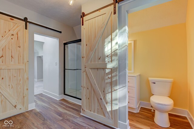 bathroom featuring walk in shower, a textured ceiling, toilet, and hardwood / wood-style flooring