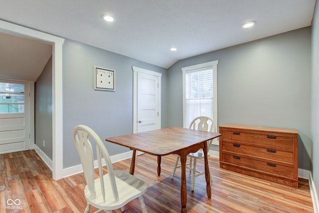 dining space featuring light wood-type flooring and vaulted ceiling