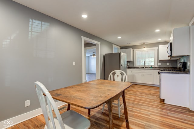 dining room featuring ceiling fan, sink, and light hardwood / wood-style floors