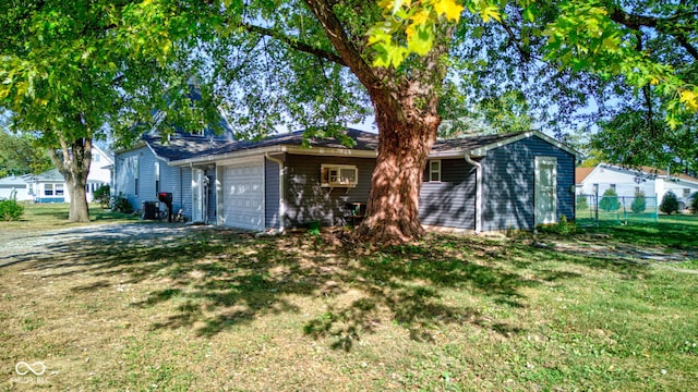 ranch-style home with a garage, fence, and a front lawn