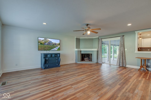 unfurnished living room featuring a brick fireplace, light wood-type flooring, and ceiling fan