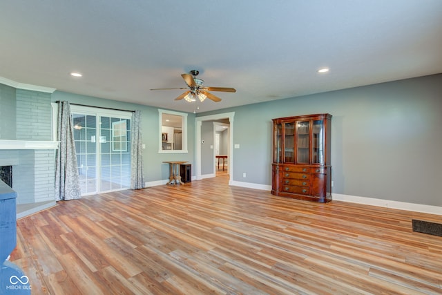 unfurnished living room with ceiling fan, a fireplace, and light hardwood / wood-style flooring