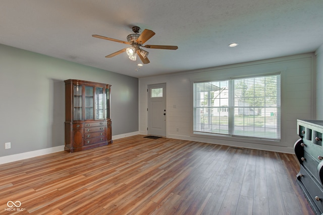 unfurnished living room with light wood-type flooring, ceiling fan, and a textured ceiling