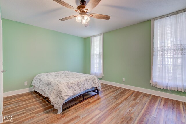 bedroom with ceiling fan, light wood-type flooring, and multiple windows