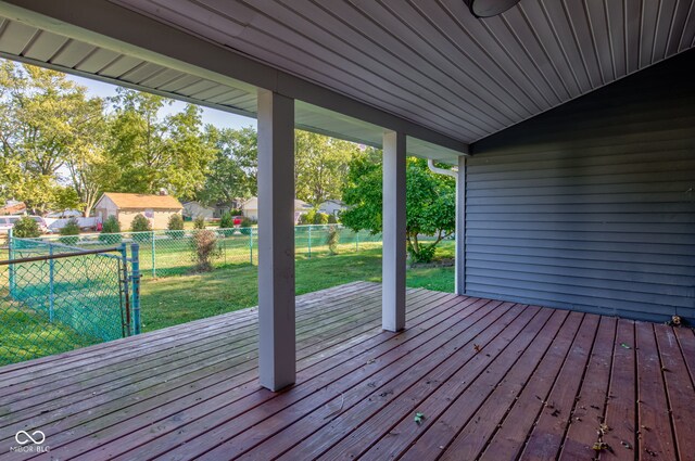 wooden deck with a storage unit and a yard