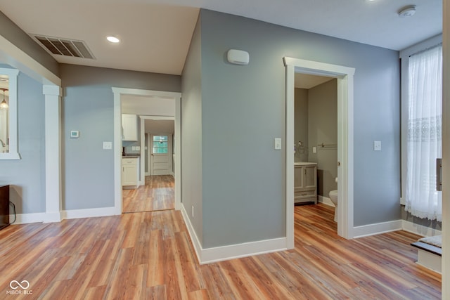 hallway featuring visible vents, baseboards, and light wood-style flooring