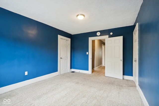 unfurnished bedroom with a textured ceiling and light colored carpet