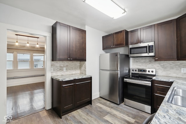 kitchen featuring decorative backsplash, light wood-type flooring, appliances with stainless steel finishes, and pendant lighting