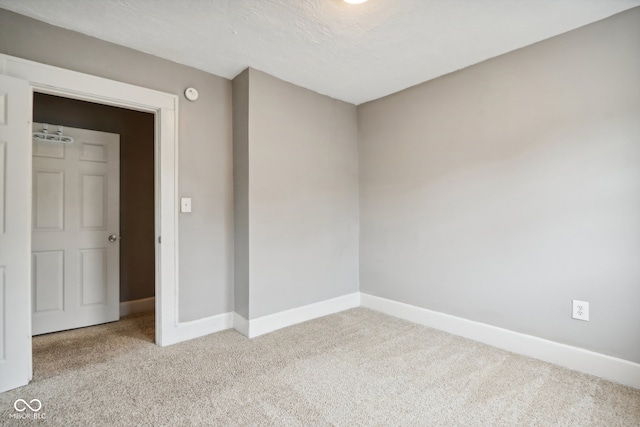 spare room featuring light colored carpet and a textured ceiling