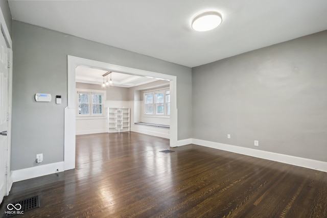 empty room featuring an inviting chandelier and dark hardwood / wood-style floors