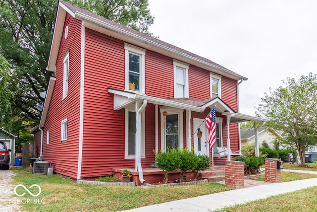 view of front of home with a front lawn, central AC unit, and a porch