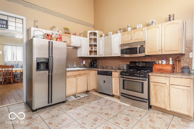 kitchen featuring decorative backsplash, stainless steel appliances, light brown cabinets, and sink