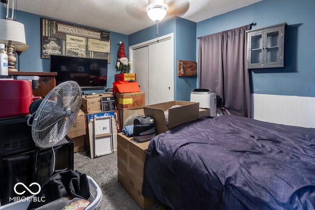 carpeted bedroom with a textured ceiling, radiator heating unit, ceiling fan, and a closet