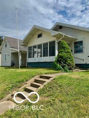 back of house with a sunroom and a lawn