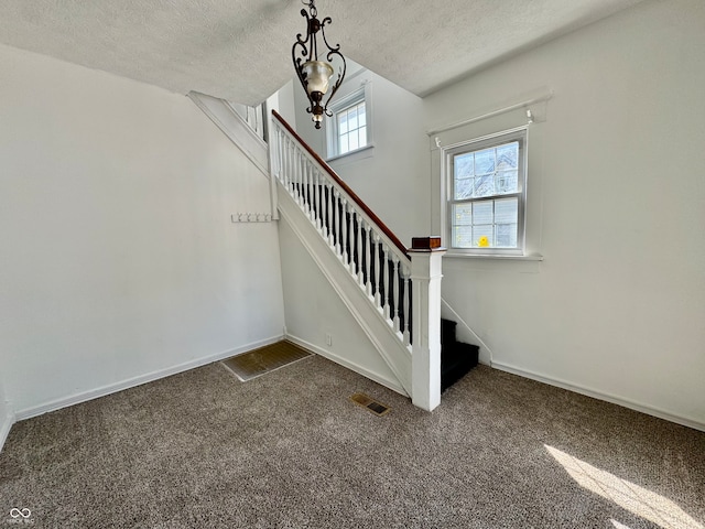 staircase featuring a textured ceiling and carpet