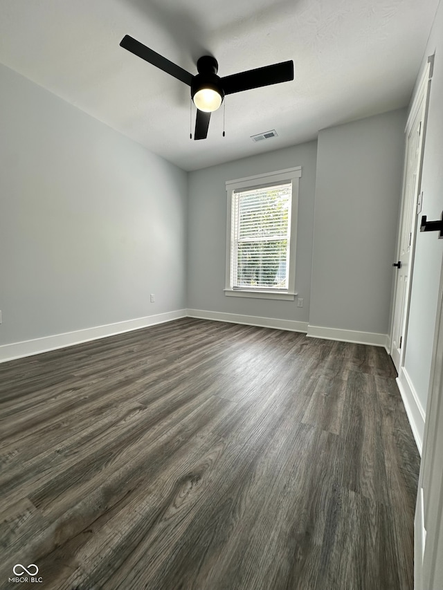 empty room with ceiling fan and dark hardwood / wood-style flooring