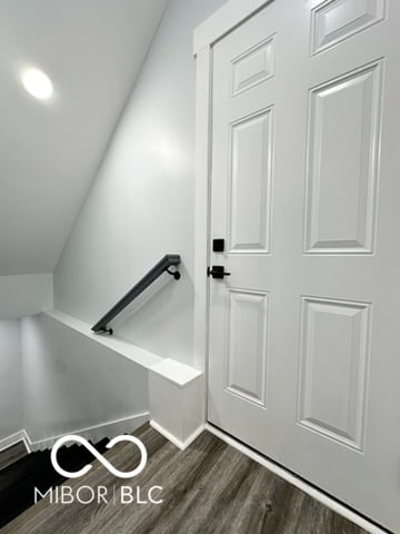 stairway with lofted ceiling and wood-type flooring