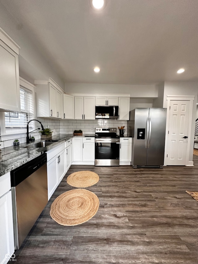 kitchen featuring stainless steel appliances, white cabinetry, sink, light stone countertops, and dark wood-type flooring