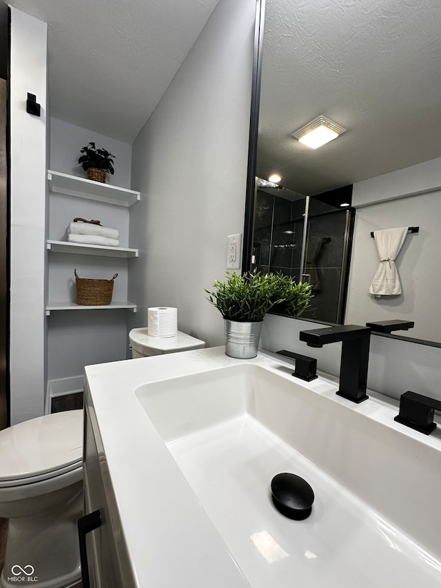 bathroom featuring walk in shower, vanity, a textured ceiling, and toilet