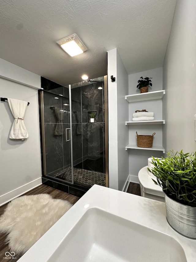 bathroom with hardwood / wood-style floors, walk in shower, a textured ceiling, and sink