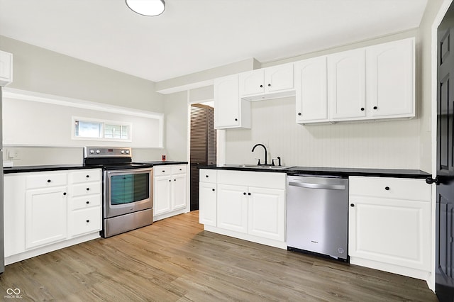 kitchen with sink, light hardwood / wood-style flooring, stainless steel appliances, and white cabinets