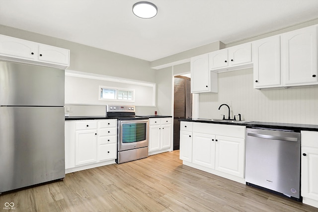 kitchen with light wood-type flooring, white cabinetry, appliances with stainless steel finishes, and sink