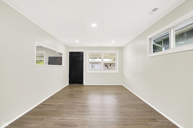 empty room featuring hardwood / wood-style flooring, ornamental molding, and a healthy amount of sunlight