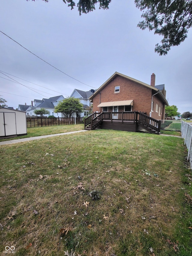 back of house with a shed and a lawn