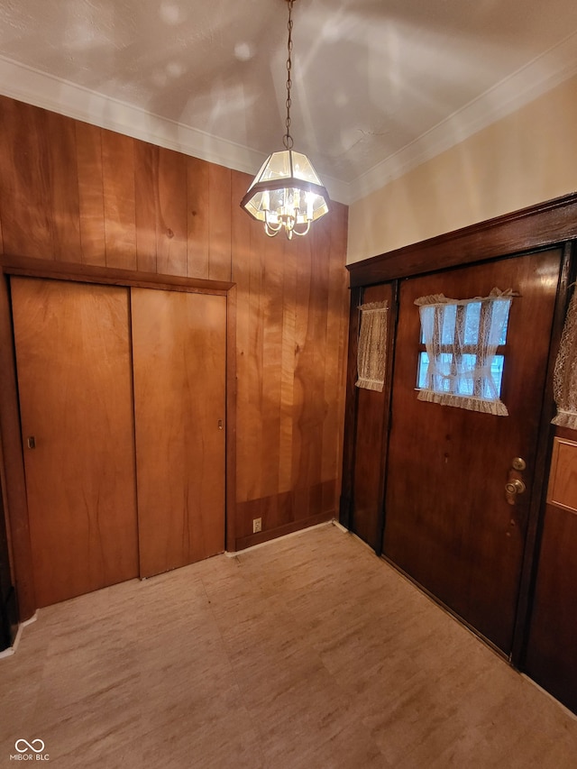 foyer with wood walls, a chandelier, and crown molding