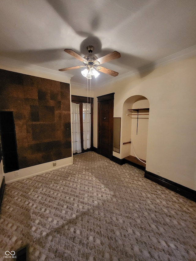 empty room featuring carpet flooring, ornamental molding, and ceiling fan