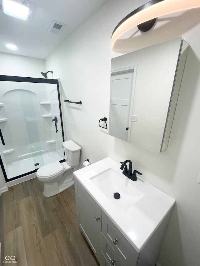 bathroom featuring vanity, toilet, an enclosed shower, and hardwood / wood-style flooring