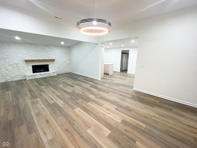 unfurnished living room featuring a stone fireplace and hardwood / wood-style floors