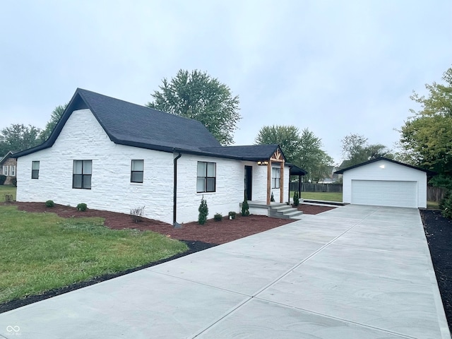 view of front of house with a front yard, a garage, and an outbuilding