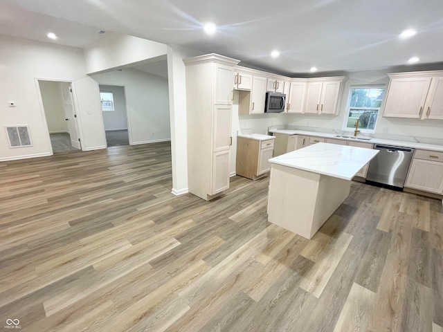 kitchen with light wood-type flooring, light stone counters, sink, a kitchen island, and stainless steel appliances