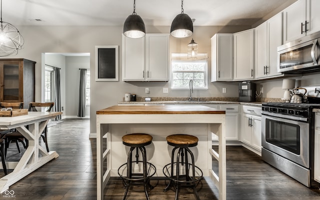 kitchen with white cabinets, sink, wooden counters, stainless steel appliances, and a center island