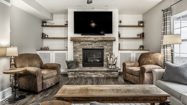 living room with dark wood-type flooring and a stone fireplace