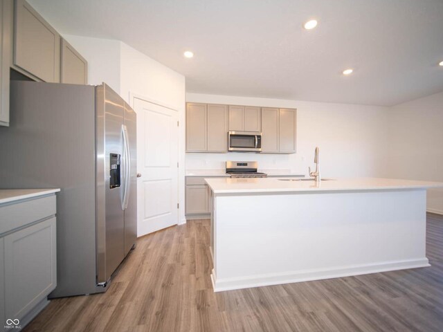 7888 Magnolia St, New Palestine, IN 46163 - kitchen featuring stainless steel appliances, light wood-style floors, gray cabinets, light countertops, and an island with sink