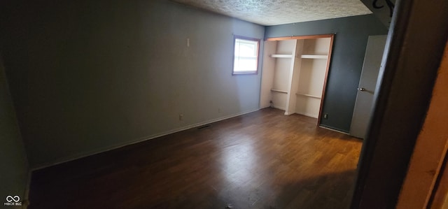 unfurnished bedroom featuring a textured ceiling, dark hardwood / wood-style floors, and a closet