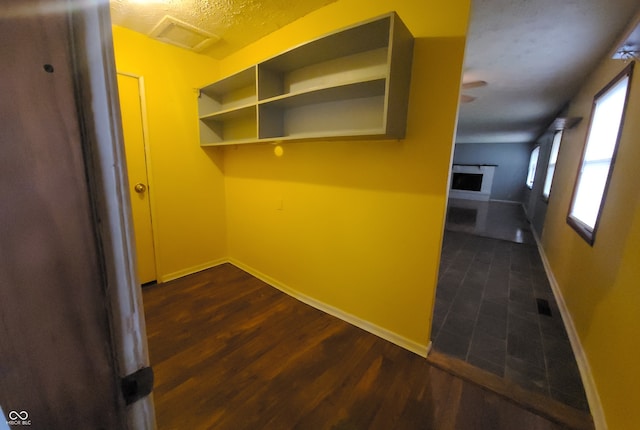 corridor with a textured ceiling and dark wood-type flooring