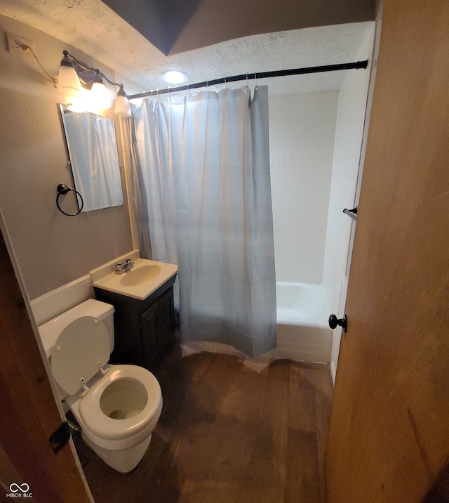 full bathroom with shower / bath combination with curtain, a textured ceiling, hardwood / wood-style flooring, vanity, and toilet