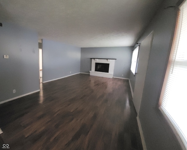 unfurnished living room featuring a textured ceiling and dark hardwood / wood-style floors