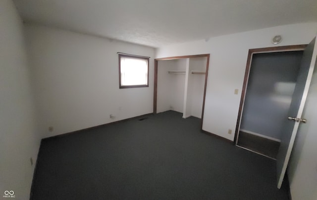 unfurnished bedroom featuring dark carpet and a closet