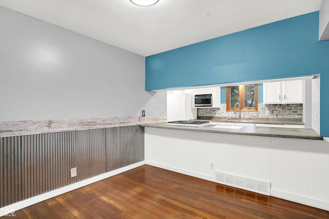 kitchen with white cabinetry, backsplash, stainless steel gas cooktop, dark hardwood / wood-style floors, and sink