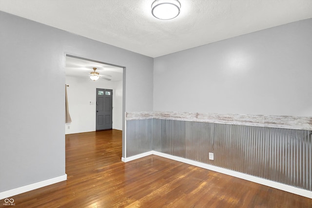 empty room featuring a textured ceiling, dark wood-type flooring, and ceiling fan