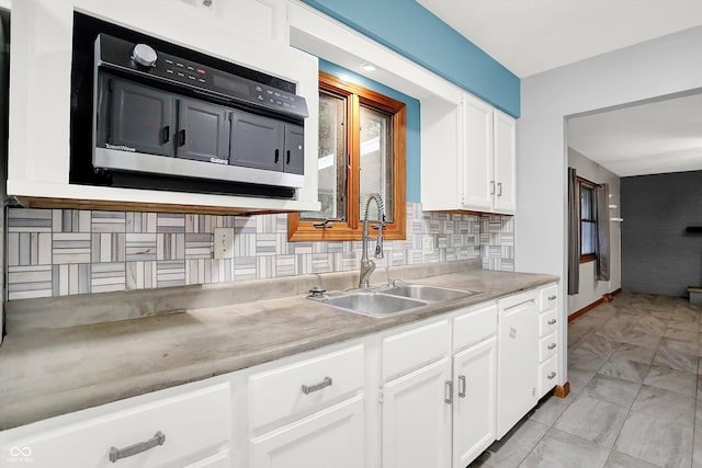 kitchen featuring tasteful backsplash, light tile patterned flooring, sink, and white cabinets