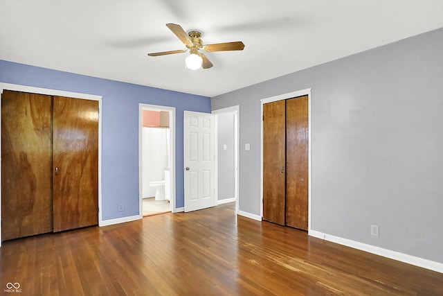 unfurnished bedroom featuring wood-type flooring, two closets, ensuite bathroom, and ceiling fan