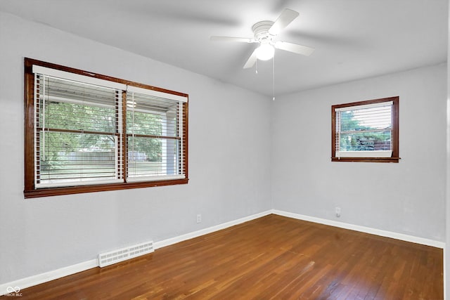 spare room with dark hardwood / wood-style floors, ceiling fan, and plenty of natural light