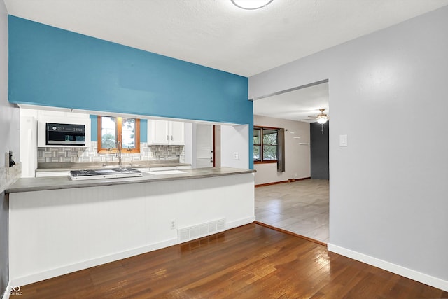 kitchen featuring ceiling fan, white cabinets, a textured ceiling, backsplash, and dark wood-type flooring